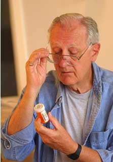 man attempting to read a small prescription bottle label