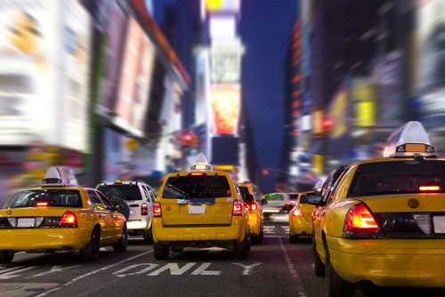 Times Square at night, the streets filled with yellow taxi cabs.