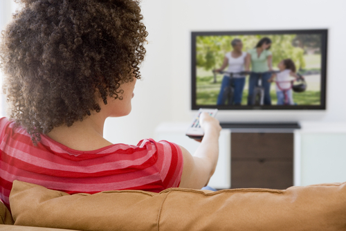 A woman on her couch watching television.