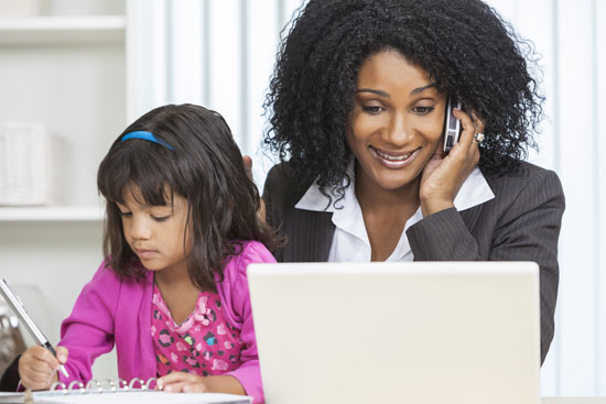 Businesswoman working on her cell phone and laptop with her daughter.