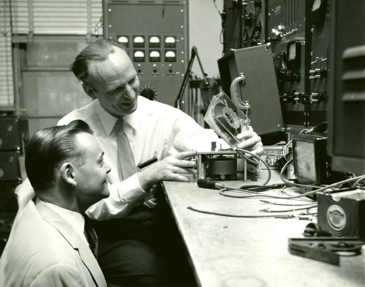 John Breuel, AFB employee, and another man check a magnetic tape cartridge at the American Foundation for the Blind, 1957. Talking Book Archives, American Foundation for the Blind.