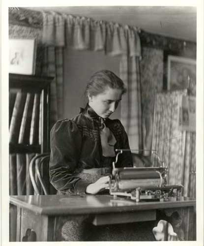 Helen Keller as a young college student typing on an old-fashioned machine. 