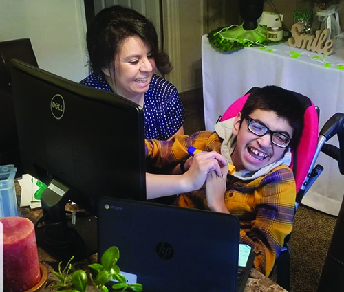 A Hispanic high school student who is deafblind and his mother smile as they work on number recognition with his TVI via Zoom. 