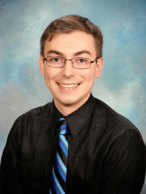 Andrew Worley wearing dark shirt and striped tie. 