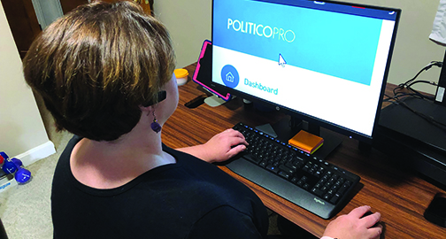 View over the shoulder of a woman siting at a computer as she looks at a monitor with very large text