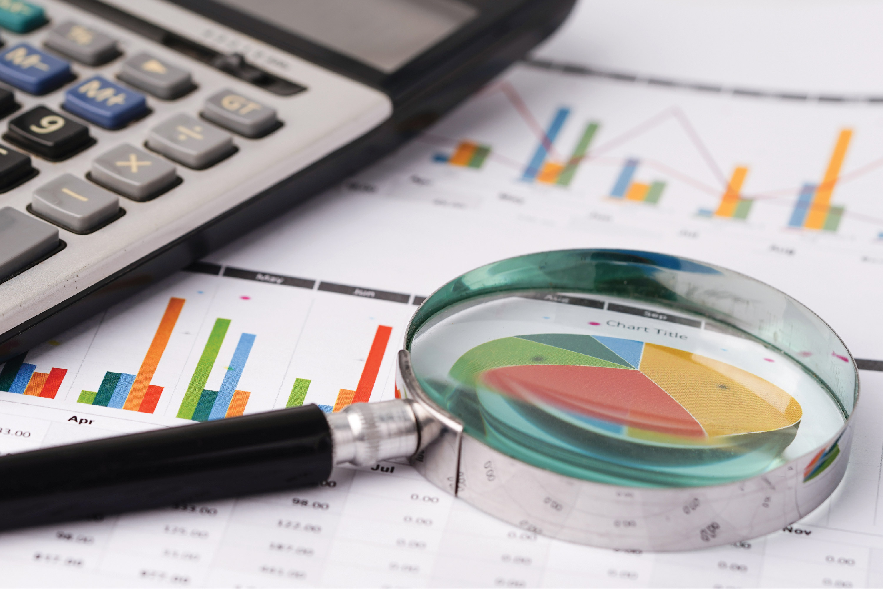 Magnifying glass lays on a paper of colorful graphs.