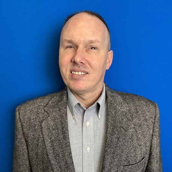 Matthew Janusauskas, a smiling man with short hair, wearing a suit jacket. 