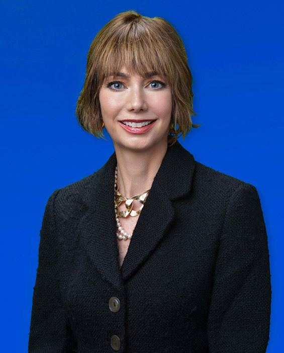 A smiling woman with bright blue eyes and chin-length brown hair. 