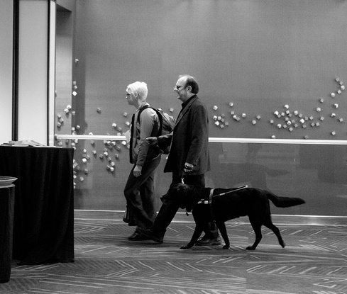 a woman, and man with dog guide, walking down the conference halls