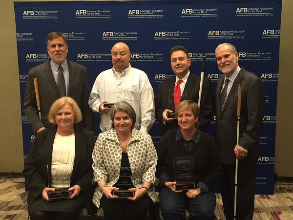 Back Row, Standing: AFB President of Programs and Policy Paul Schroeder; Ed Gray of Avid Technology; NFB President Mark Riccobono; AFB President and CEO Carl Augusto. Front Row, Seated: Glinda Foster Hill; ITNAmerica Founder and President Katherine Freund; Netflix Director of Global Operations Tracy Wright