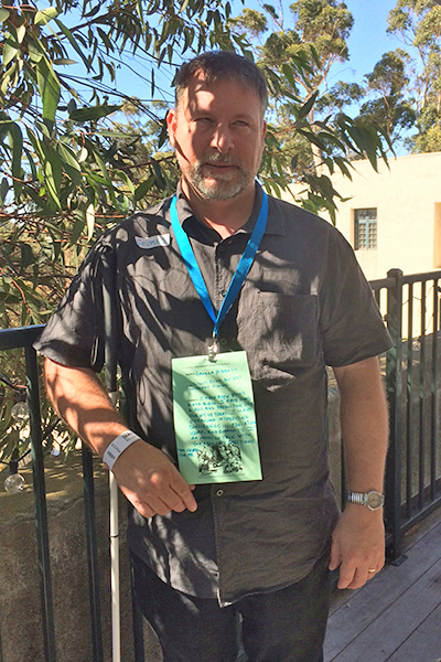 George Abbott, wearing sunglasses and a lanyard with a piece of green paper clipped to it.