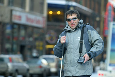 A man with a cane using the Trekker on a city street.