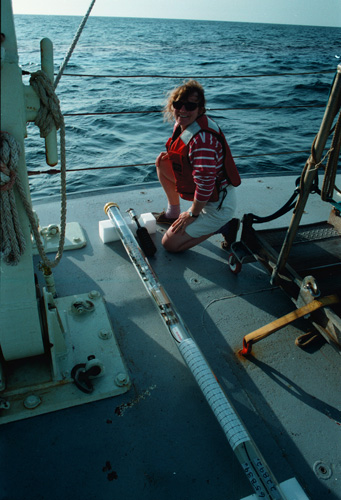 Photo of Amy Bower crouching on a ship's deck with a measurement instrument.