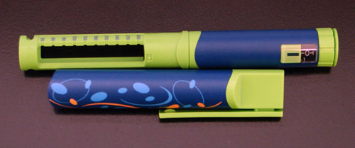 Photo of Novopen Junior, which is bright green and blue and decorated with swirls.