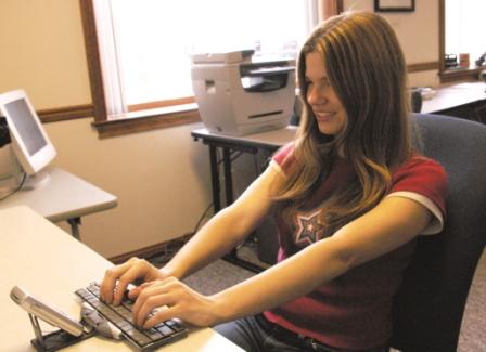 Photo of woman using a small keyboard with a cell phone sitting on the attached stand.