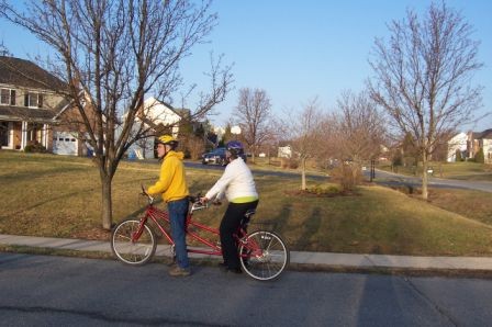 A sighted and visually impaired cyclist ride a tandem bike.