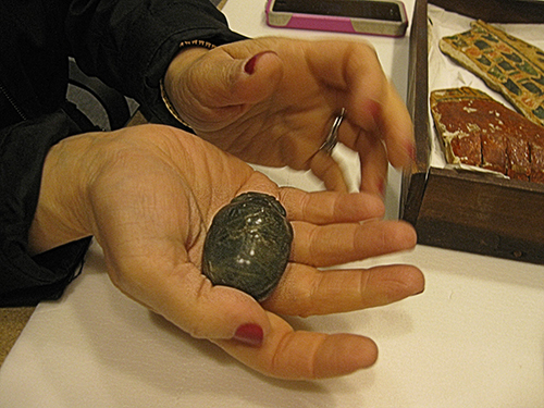 A closeup of the carved scarab in a visitor's hand